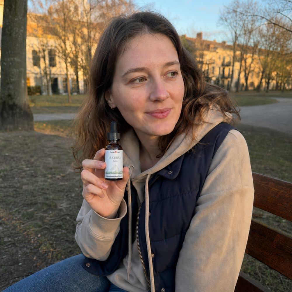 Kvinna som håller en flaska Lucerne CBD olja utomhus i en park